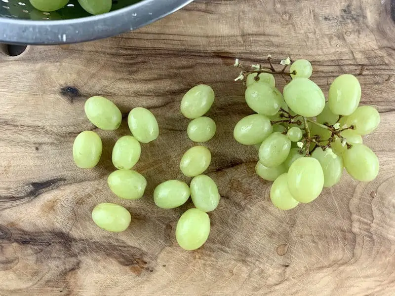 PICKING GRAPES FROM STEMS ON WOODEN BOARD