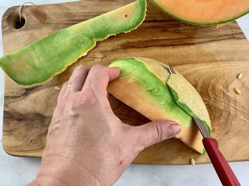 HANDS USING A KNIFE TO PEEL A MELON