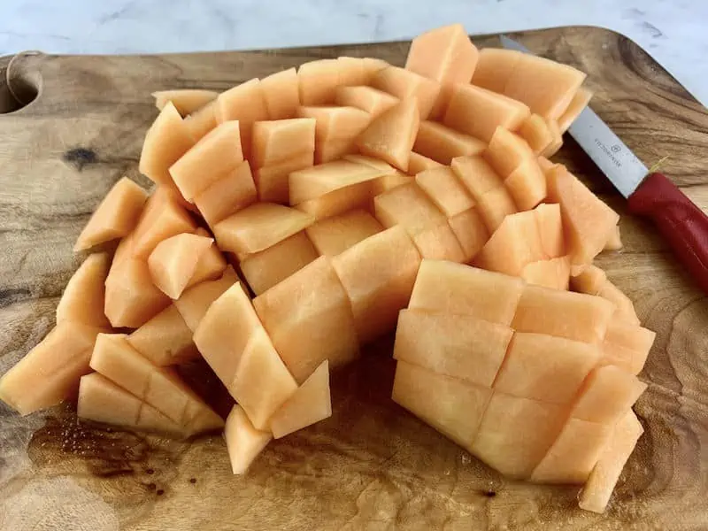 DICED MELON ON WOODEN BOARD WITH KNIFE ON THE SIDE