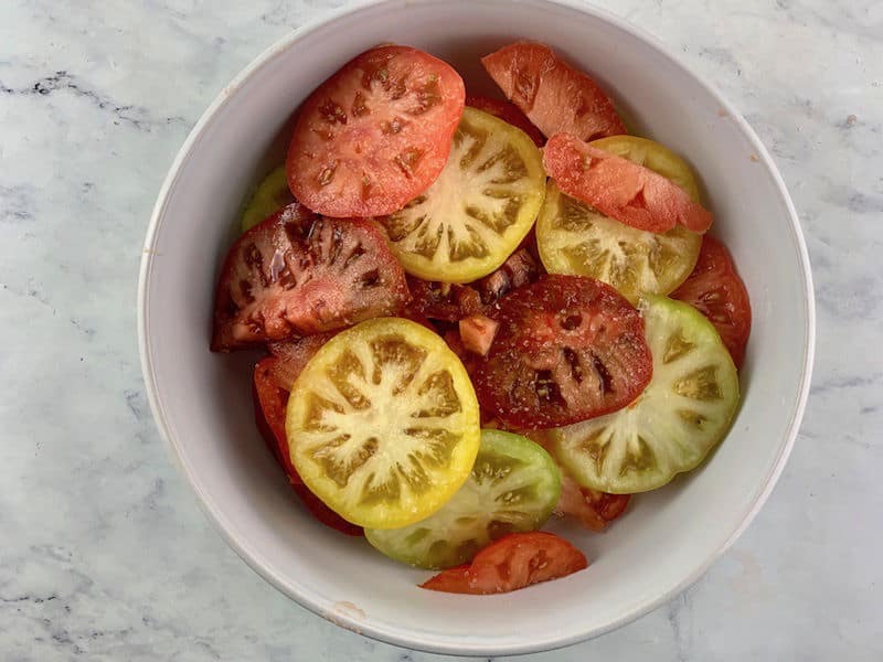 SLICED HEIRLOOM TOMATOES IN WHITE BOWL WITH SALT