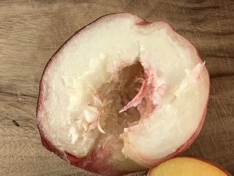 WHITE PEACH ON WOODEN BOARD WITH PIT REMOVED