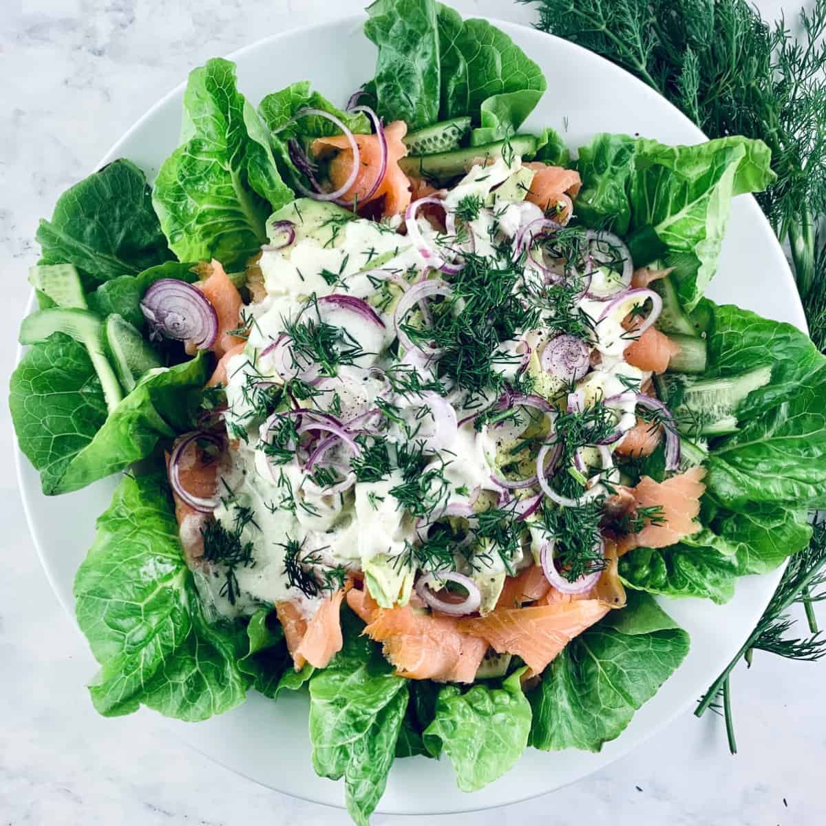 Smoked Salmon Avocado Salad on a white platter with fresh dill on top right corner.