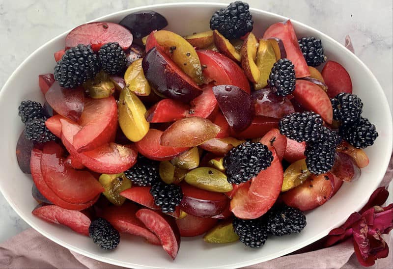 PLUM SALAD IN A WHITE BOWL GARNISHED WITH BLACKBERRIES
