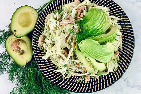 Smoked trout & fennel salad on a patterned platter with dill & avocado on the side.
