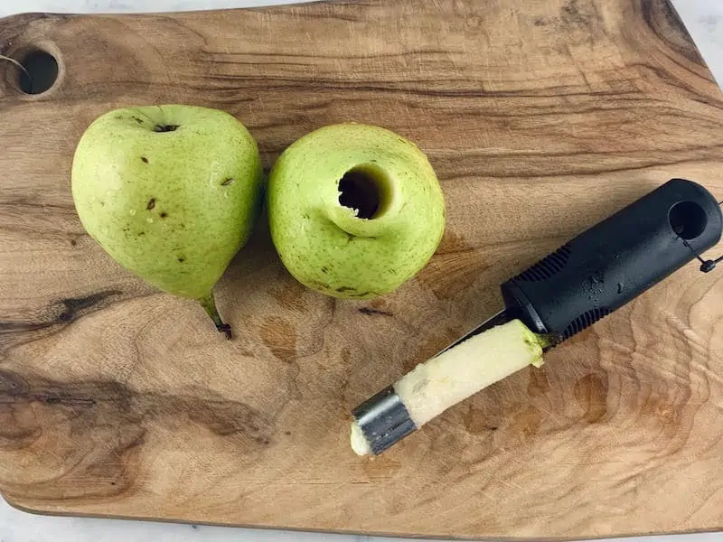 PEARS ON WOODEN BOARD ONE THAT HAS BEEN CORED WITH APPLE CORER ON SIDE