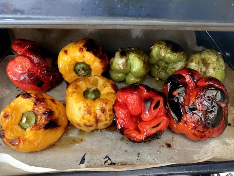 Charred roasted peppers on a baking tray.