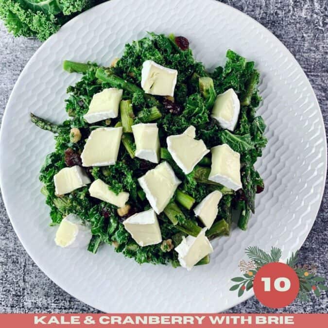 Kale and Cranberry Salad topped with Brie on a white platter, with Xmas text overlay..