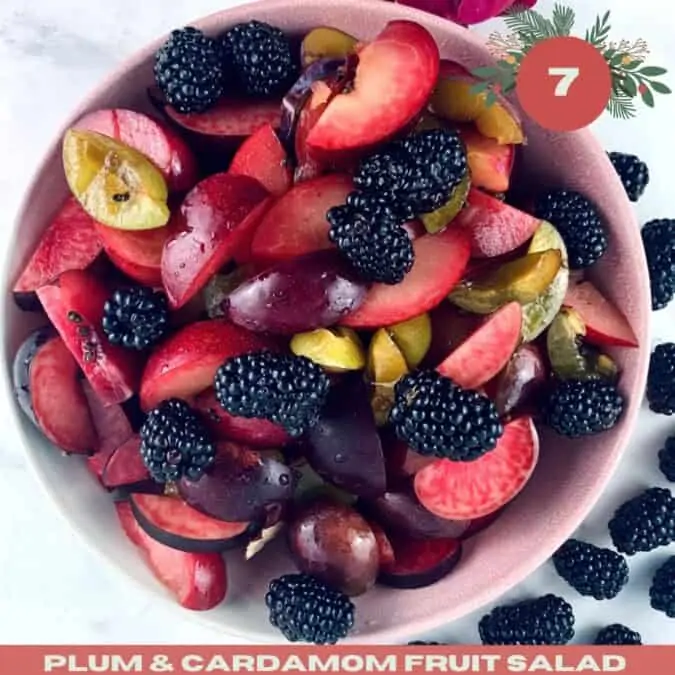 Plum Salad with Blackberries in a pink bowl with blackberries scattered on the side. And a Xmas text overlay.