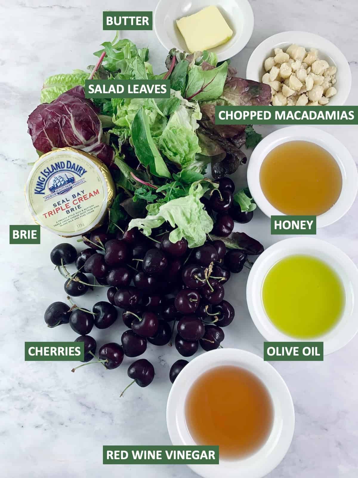 Labelled ingredients needed to make brie salad with cherries.