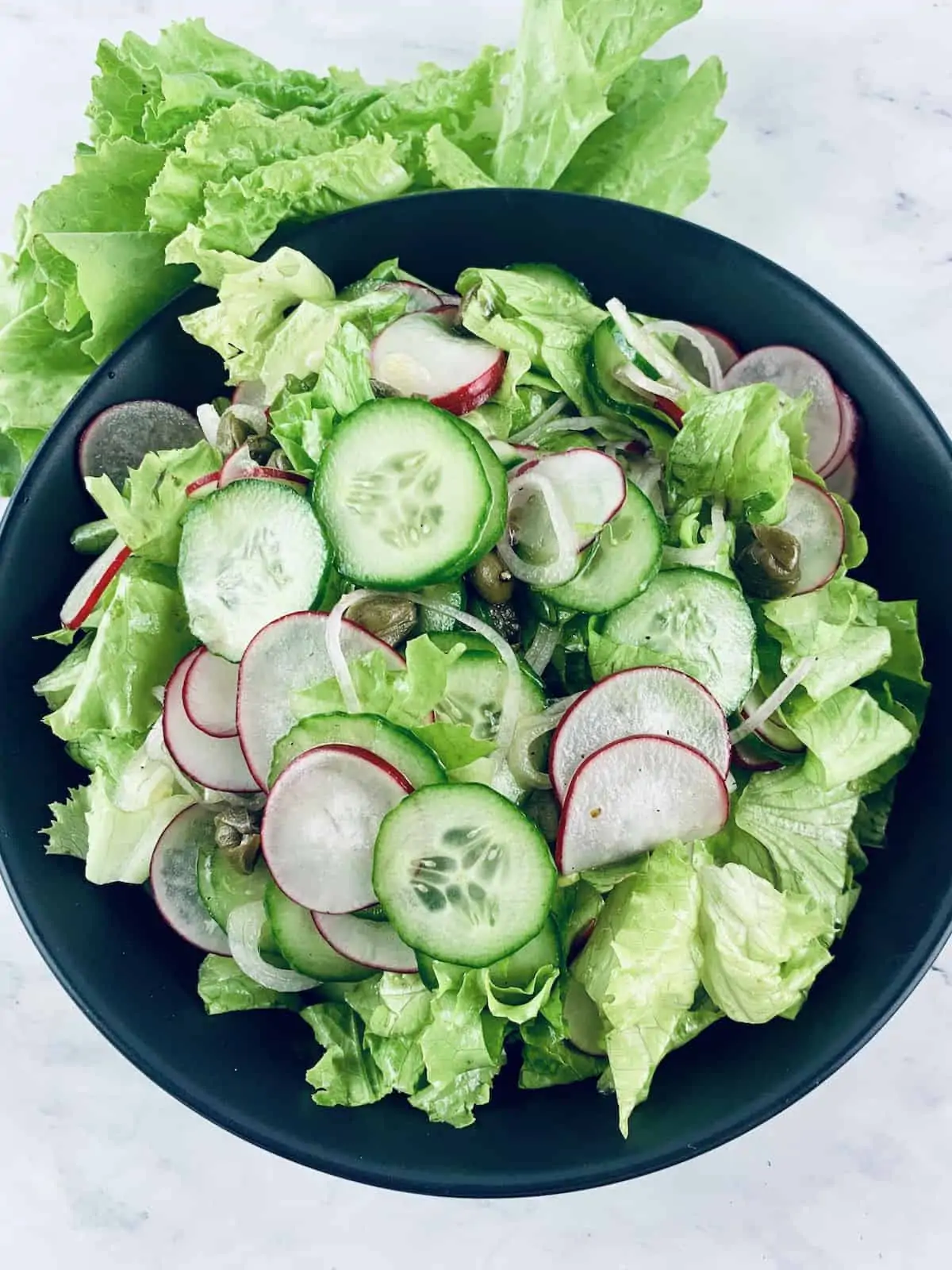 xRadish Green Salad in a black bowl with lettuce leaves up top.