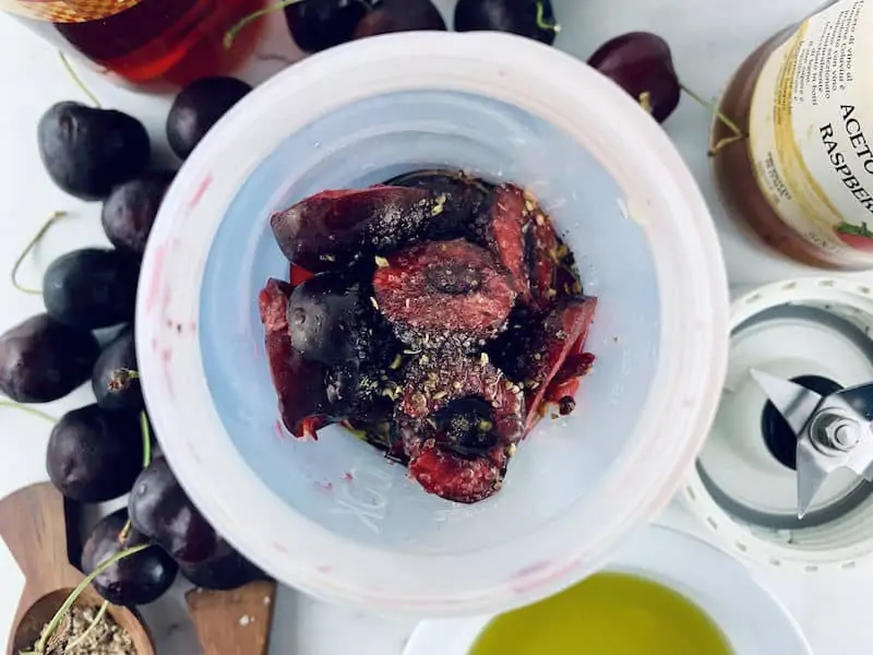 Cherry vinaigrette ingredients in blender with ingredients scattered around.
