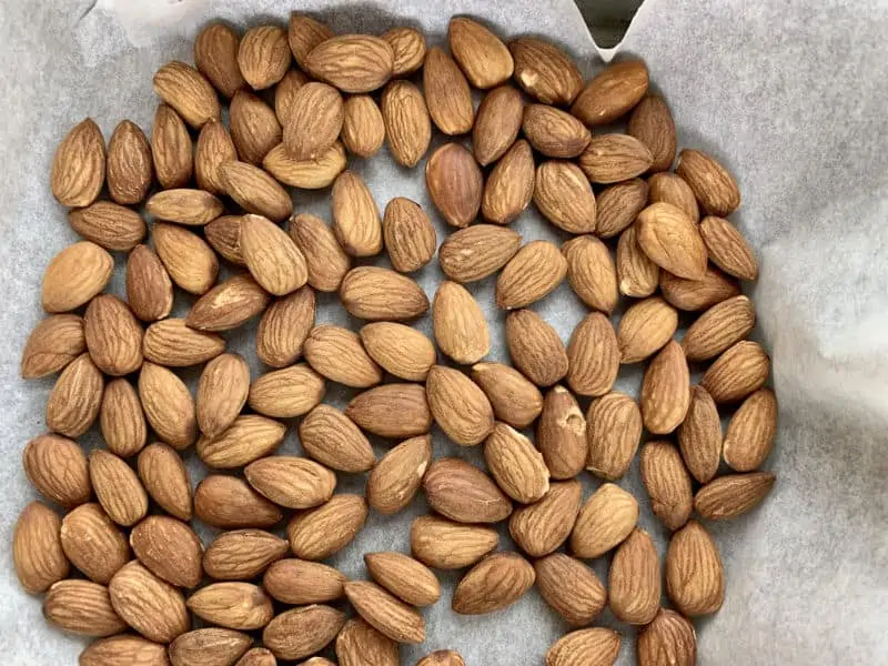 Raw almonds in a baking tray lined with baking paper.