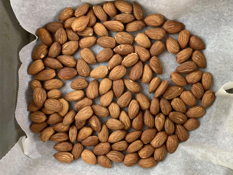 Roasted almonds in a baking tray lined with baking paper.
