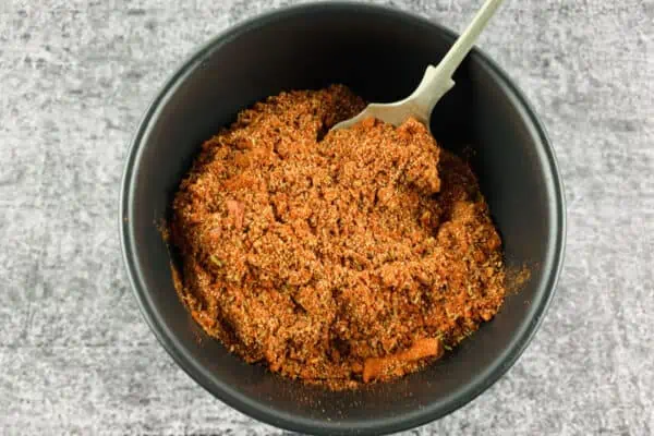 Keto-friendly taco seasoning in a black bowl with a silver spoon.