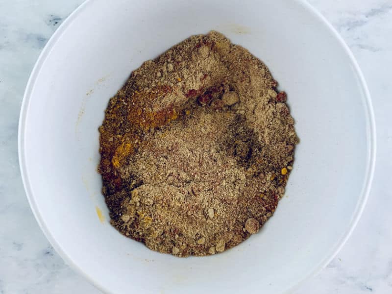 All ras el hanout spices and ground seeds in a white bowl.