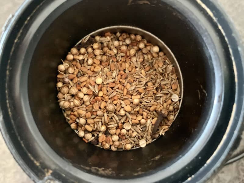 Cooled whole Madras spices in a spice grinder.
