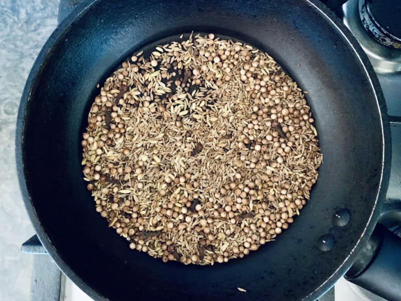 Ras el Hanout whole spices and seeds in a pan on the stove.
