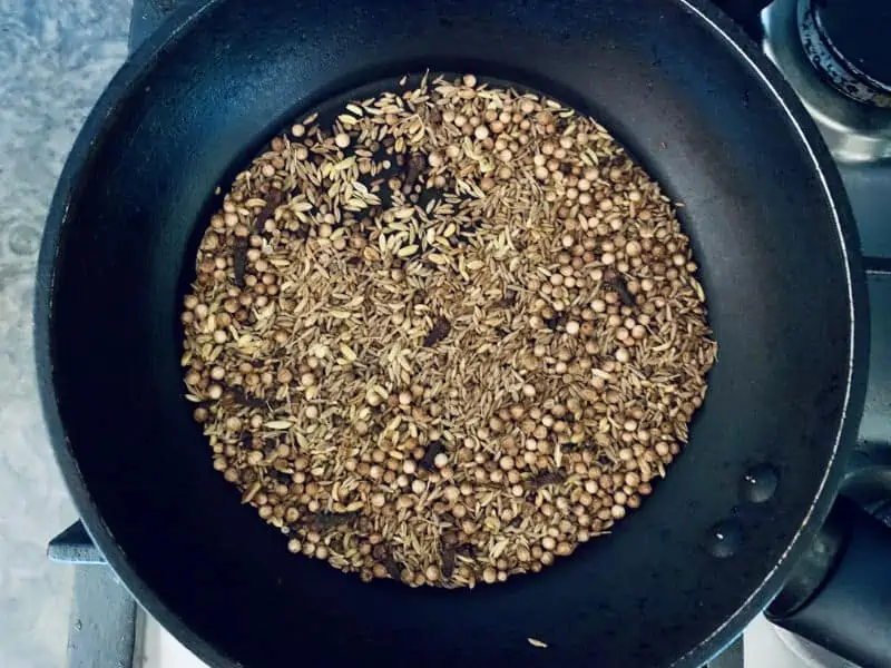 Warming ras el hanout spices in pan on the stove.