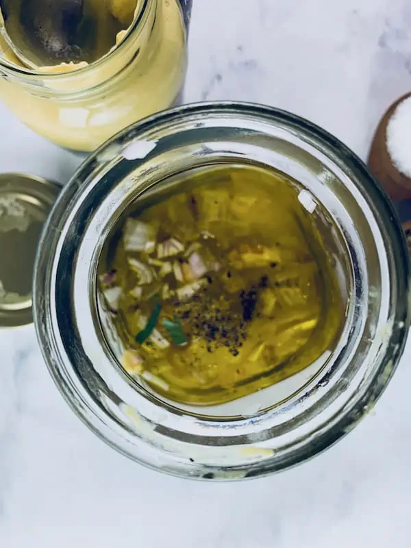 French mustard vinaigrette ingredients in a glass jar with more scattered around.