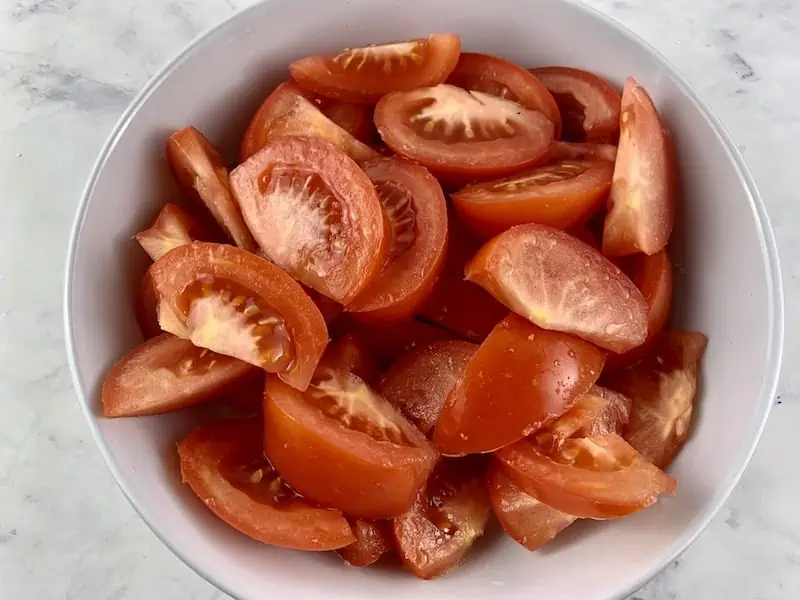 Sweated tomato wedges in a white bowl.