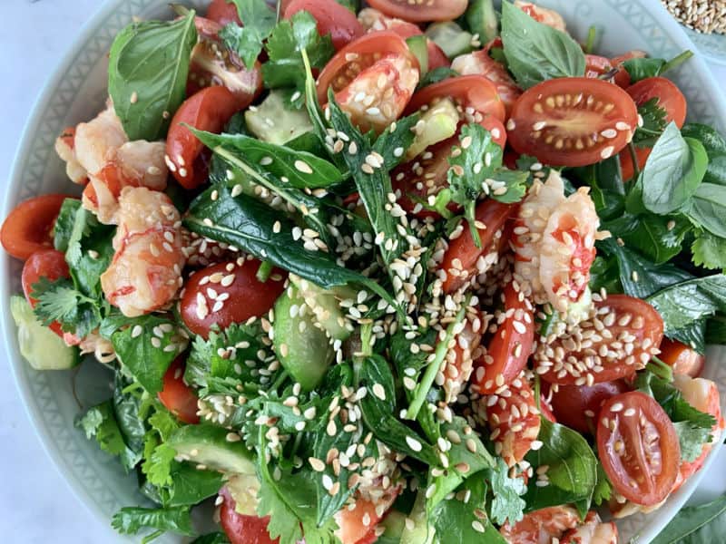 A close-up of Thai Prawn Salad in a Mint bowl with sesame seeds on top.