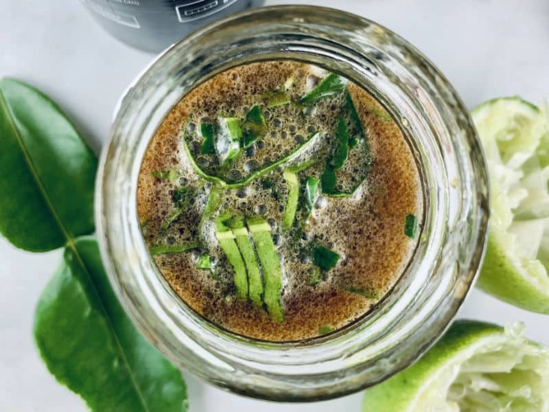 Shaken up Thai dressing in a glass jar with ingredients scattered around.
