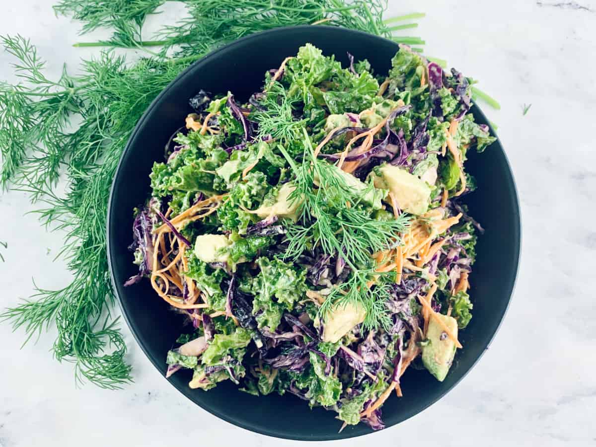 Kale Coleslaw in a black bowl with dill on the side.