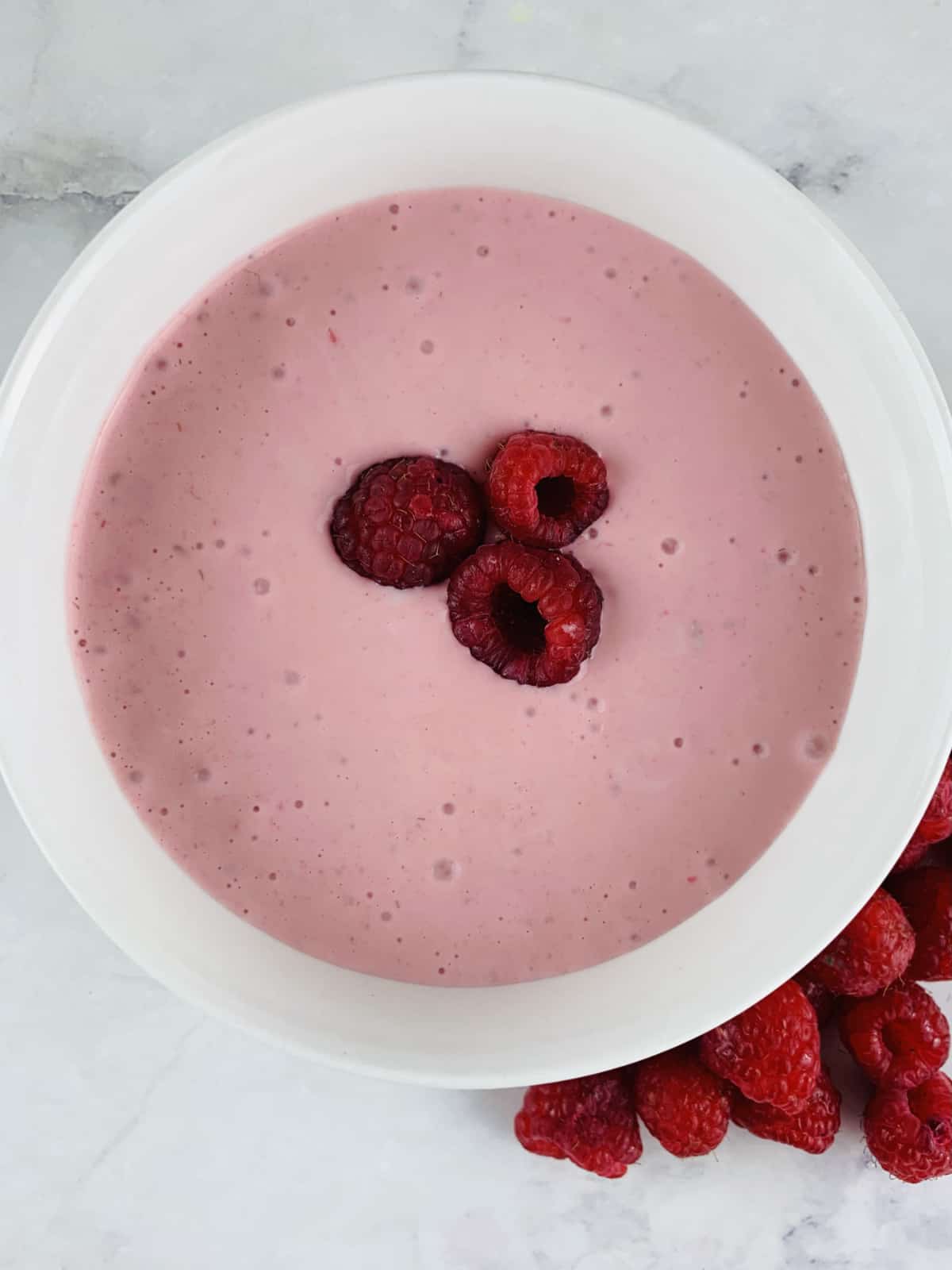 Raspberry Salad Dressing in a white bowl with raspberries on the side.