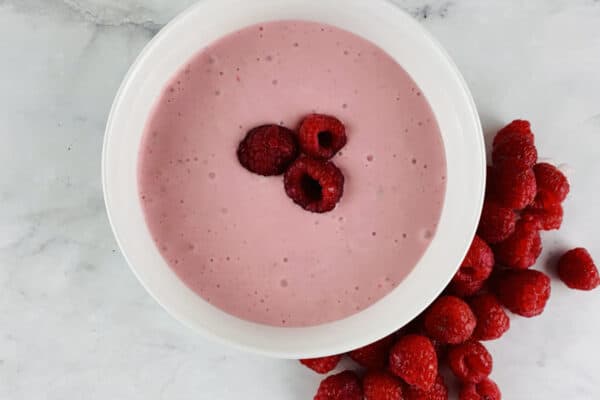 Raspberry Salad Dressing in a white bowl with raspberries on the side.
