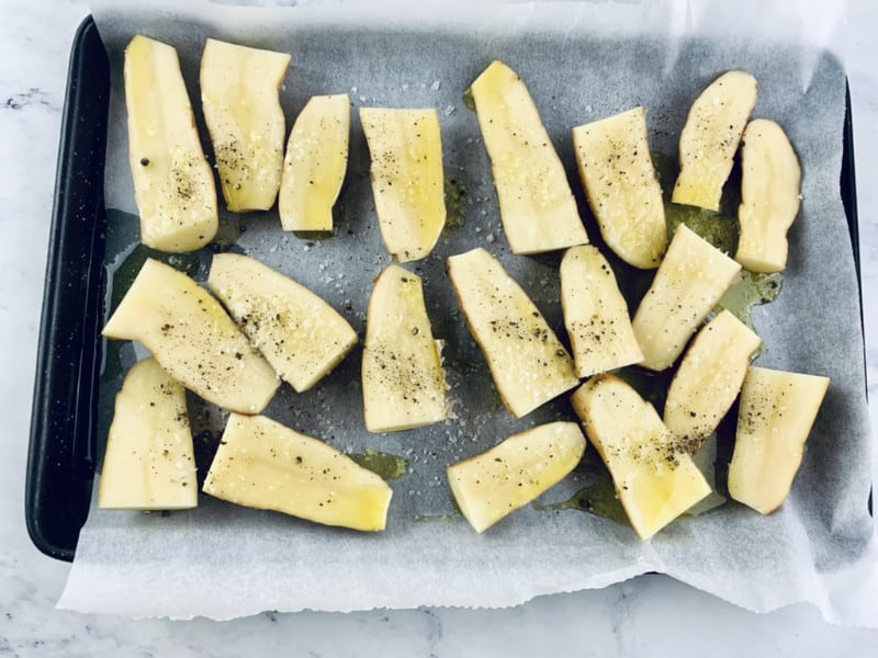Cut kipfler potatoes on a lined baking tray with oil and seasonings.