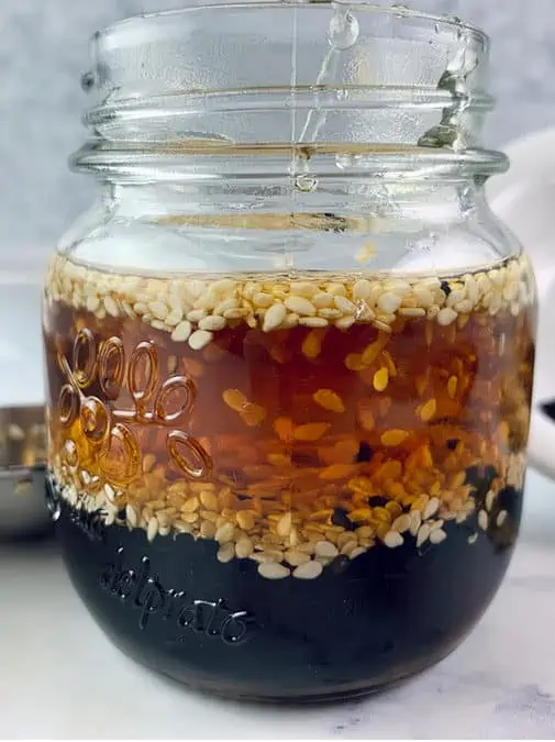 Sesame vinaigrette in a glass jar with ingredients around.
