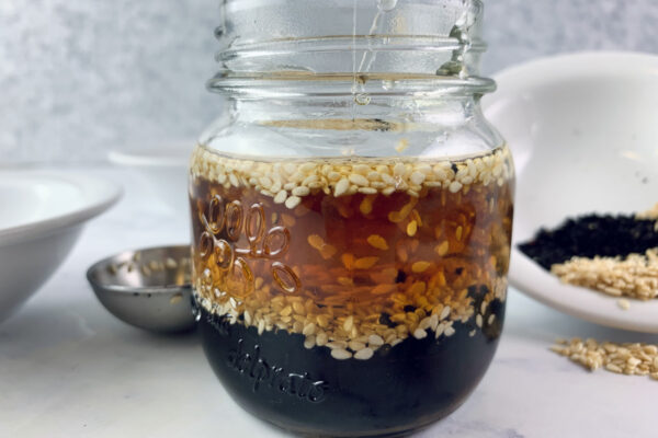 Sesame vinaigrette in a glass jar with ingredients around.