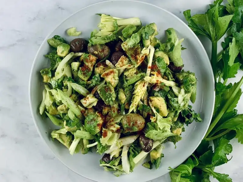 Chilean celery avocado salad with paprika on white plate with celery on side.