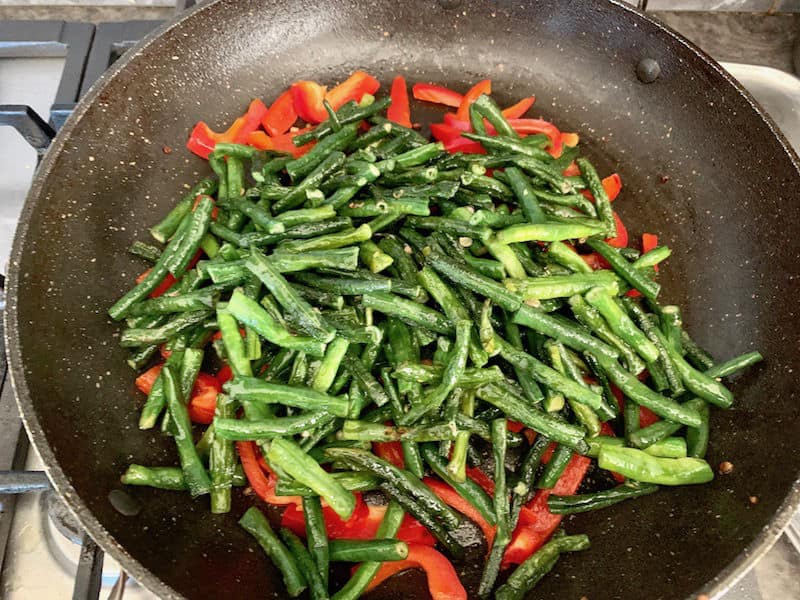 Capsicum strips and snake beans in pan.