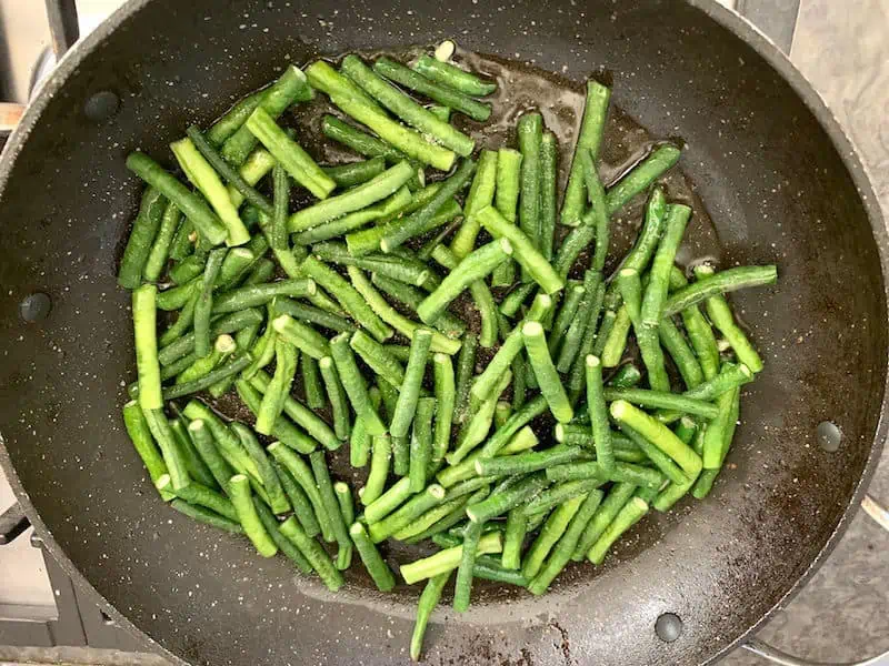 Snake beans sauteeing in pan.
