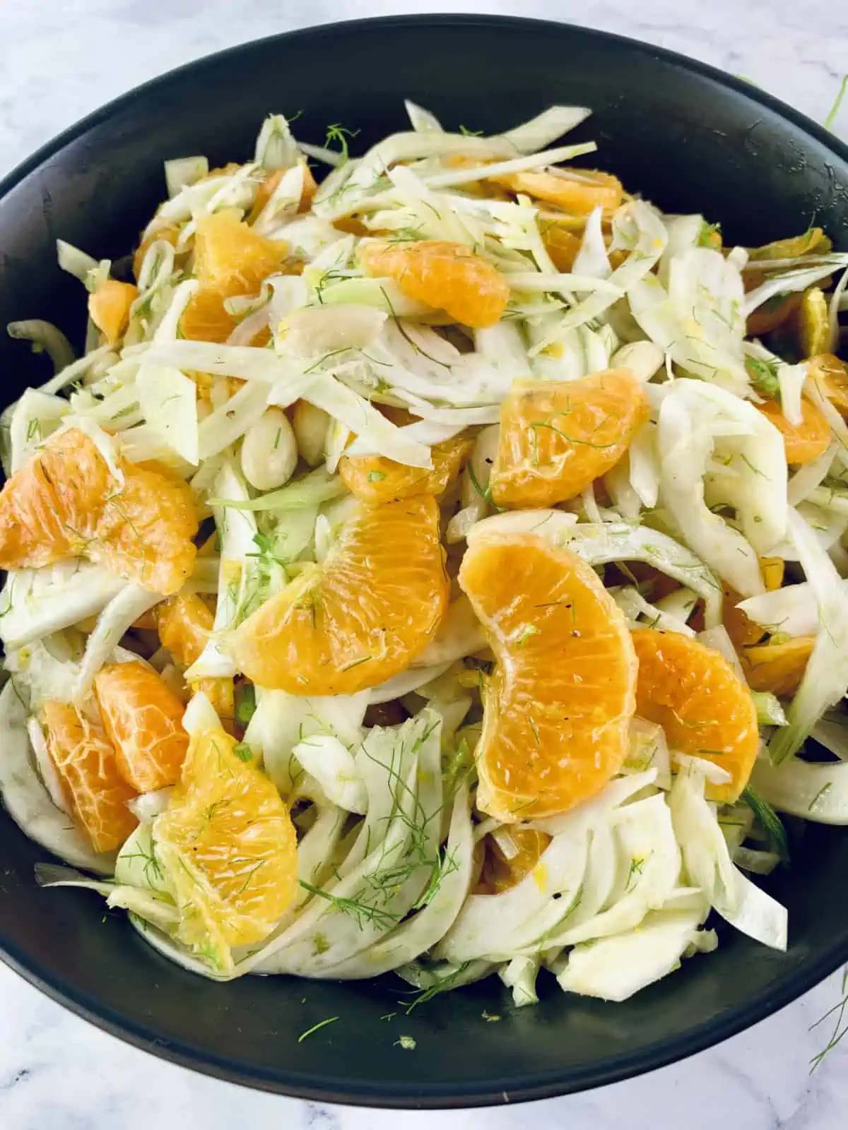 A closeup of Fennel Mandarin Salad in a black bowl.