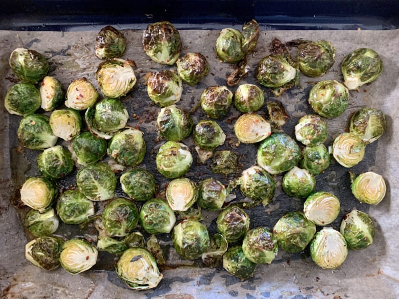 Roasted brussel sprouts in a lined pan.