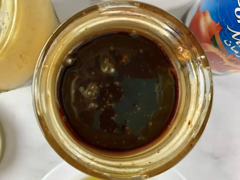 Shaken pomegranate vinaigrette in a glass jar.