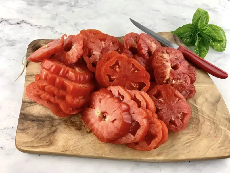 Heirloom tomatoes that have been cut into thick slices on a wooden board.