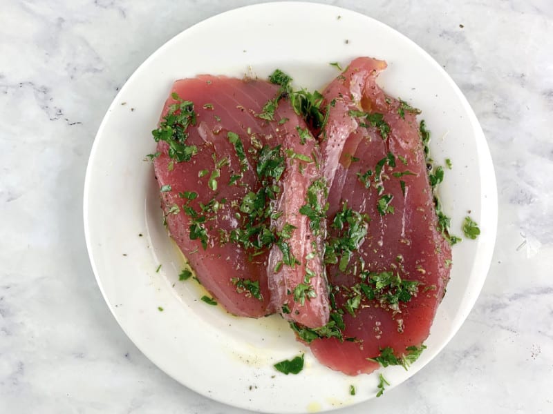 Tuna steaks on a plate coated with marinade.