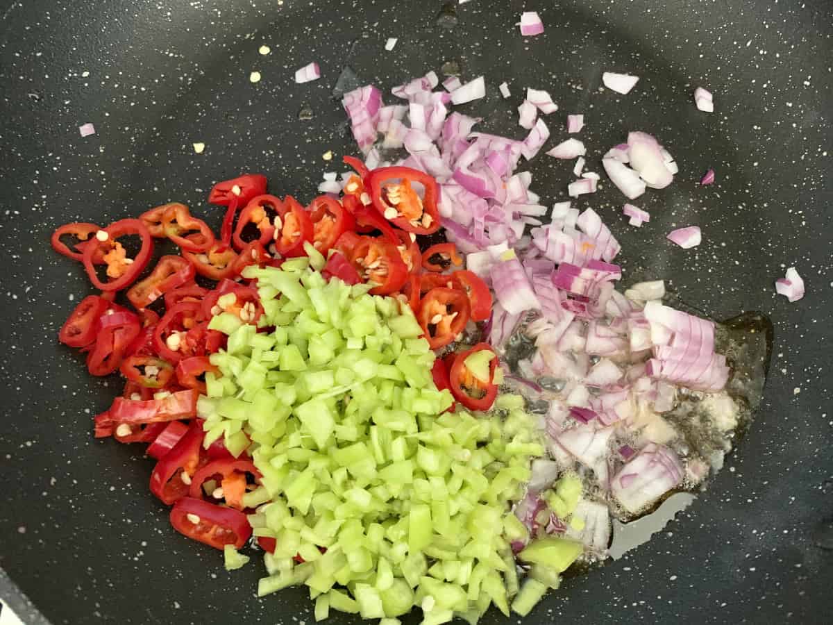 Diced peppers, chillies and onions in a hot pan with oil.