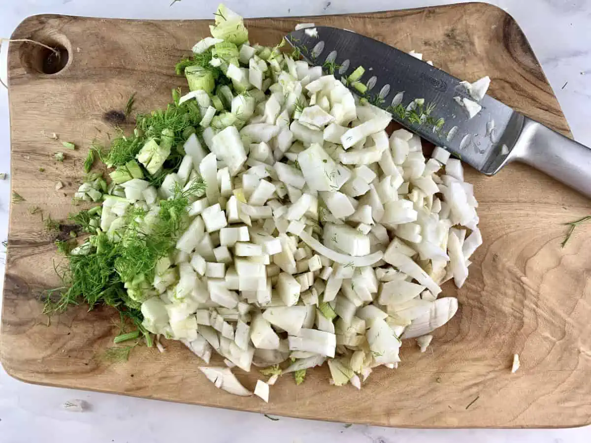 Diced fennel on a wooden board with a knife.
