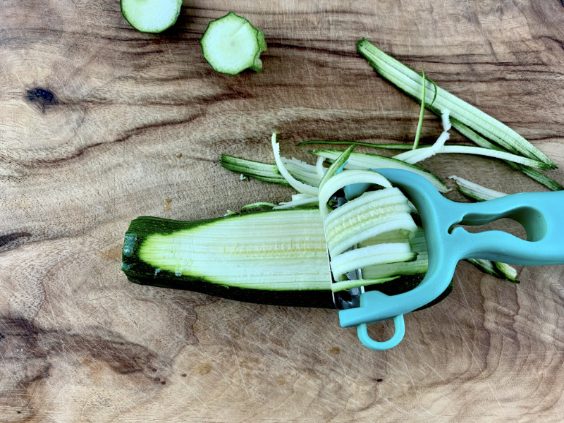 Using a julienne peeler to cut zucchini zoodles.