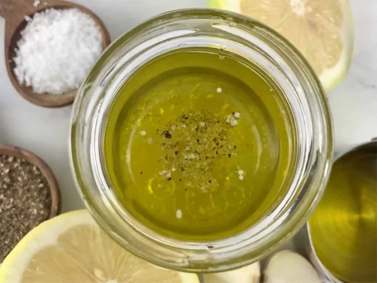 Lemon garlic vinaigrette ingredients in a glass jar with ingredients scattered around.