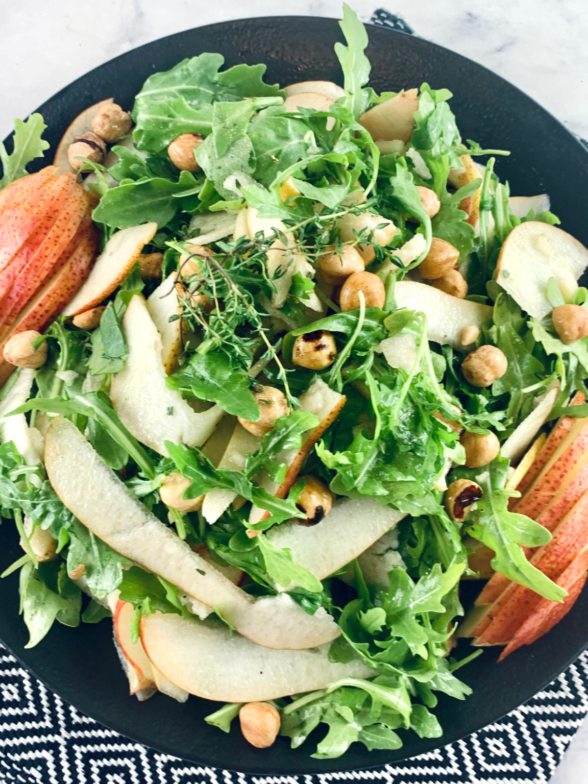 A close-up of a Pear and rocket salad on a black plate.