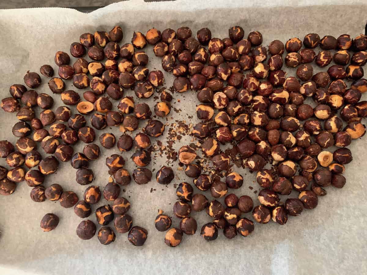 Roasted hazelnuts on a lined baking tray.