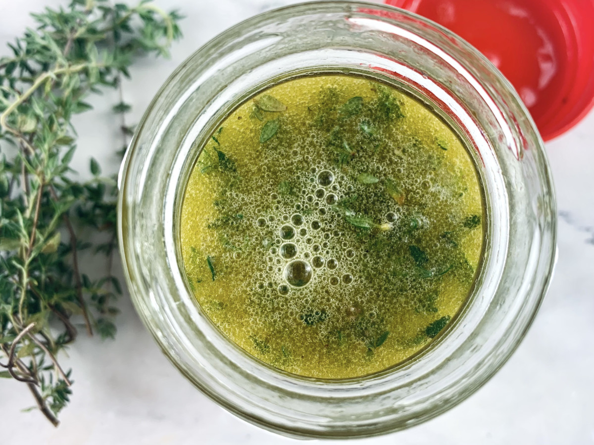 Shaken verjuice vinaigrette in a glass jar with thyme on the side.