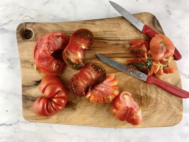 Trimming tomatoes on a wooden board.