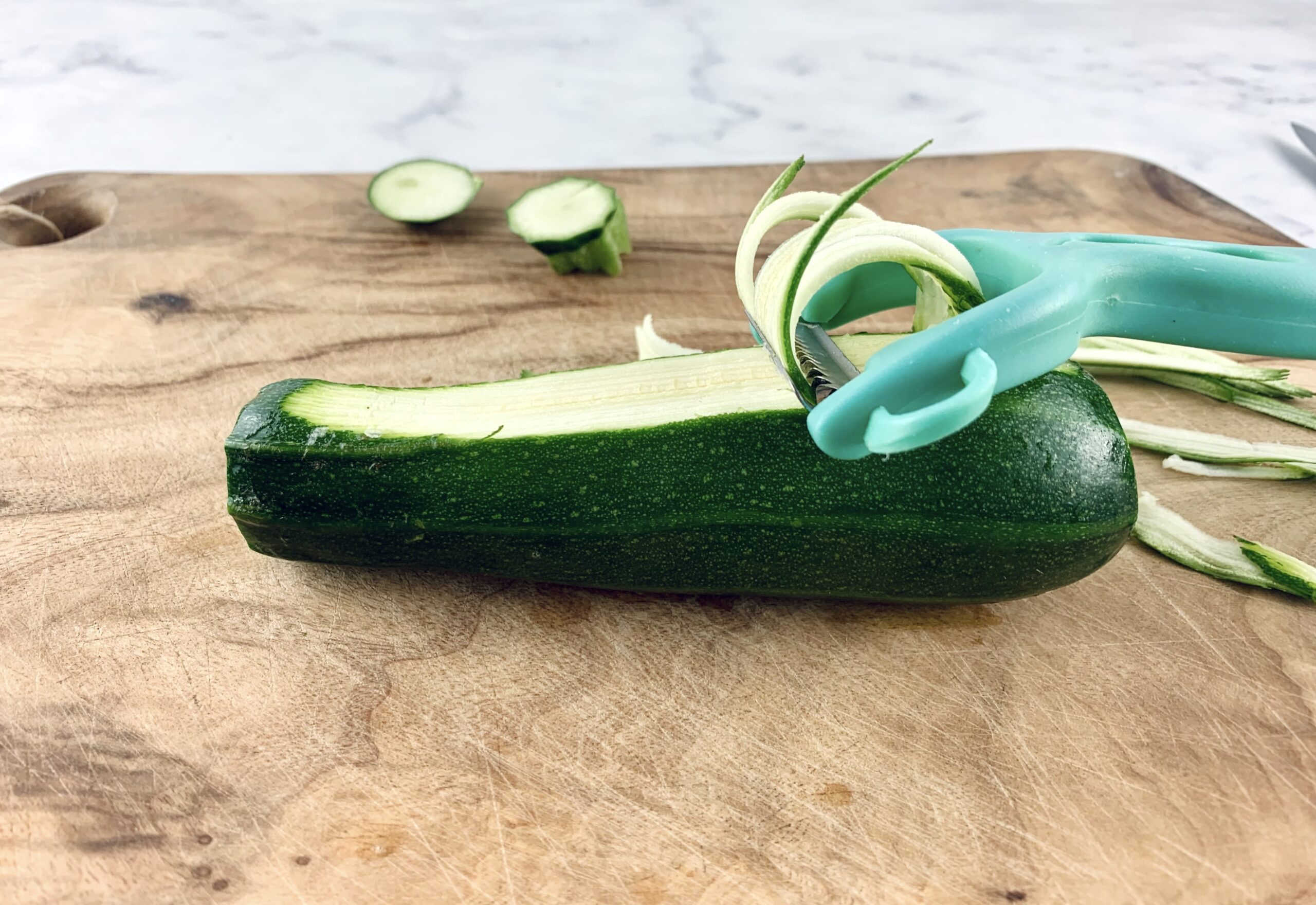 Using a julienne peeler to cut angel hair zoodles.