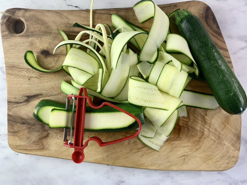 Using a vegetable peeler to cut zucchini ribbons.
